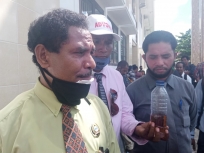 Asisten advokat Manokwari Metuzalak Awom, SH saat menunjuk bukti minyak tercampur air yang dibawa ke PN Manokwari saat mendaftar materi gugatan.