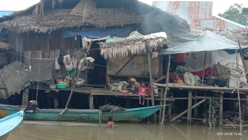 Mama Papua dan anak-anaknya berada di serambi rumah miliknya di bantaran sungai Tahiti Distrik Kota Bintuni Kelurahan Bintuni Timur pada Selasa (20/4). [Foto: JP/MW]