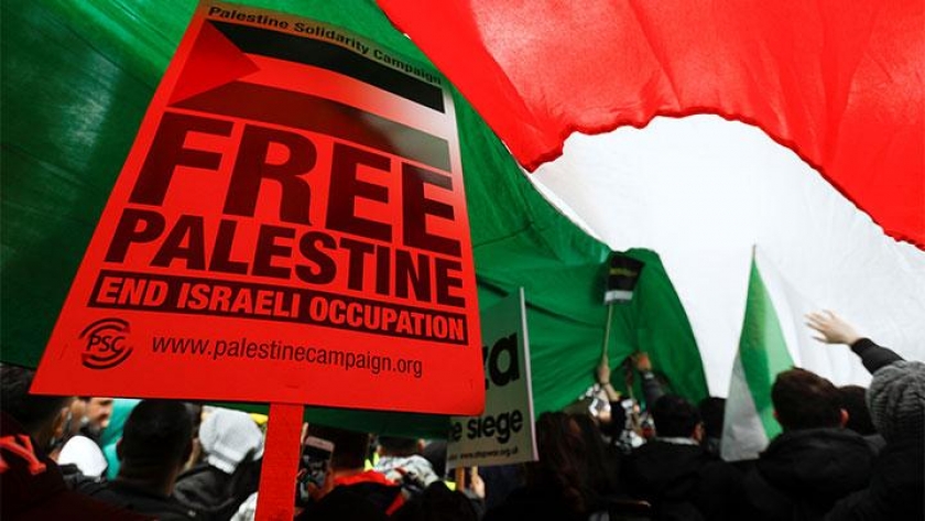 Demonstran pro-Palestina membawa poster bertuliskan bendera Palestina besar selama protes menyusul maraknya kekerasan Israel-Palestina, di London, Inggris (15/5). [Foto: REUTERS/Peter Nicholls]
